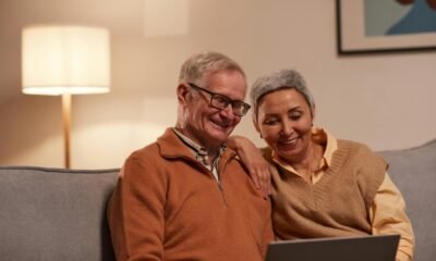 man and woman sitting on sofa while looking at a laptop