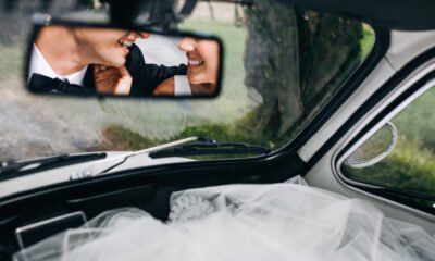 Reflection of newlyweds smiling faces in the rare window of a ca