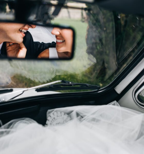 Reflection of newlyweds smiling faces in the rare window of a ca