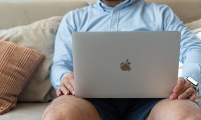 A man on a couch with a laptop, exploring online faxing software tool and its effects on business communication strategies.