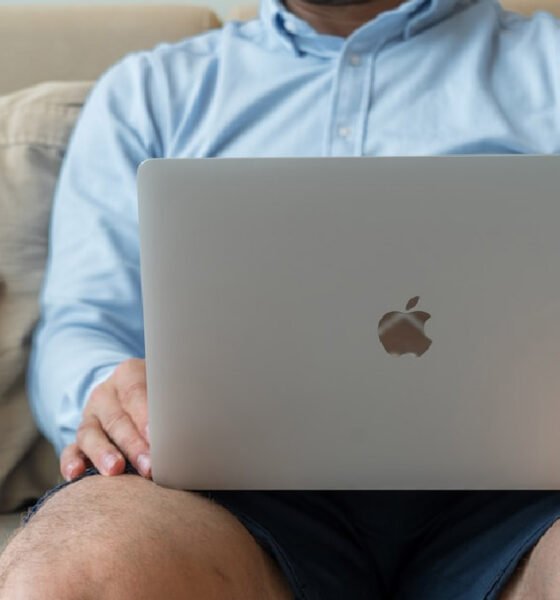 A man on a couch with a laptop, exploring online faxing software tool and its effects on business communication strategies.